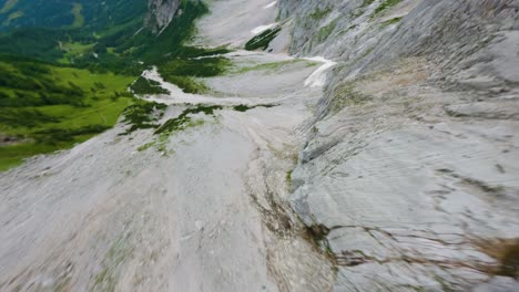 FPV-drone-dive-down-a-steep-gray-mountain-wall-in-Austria