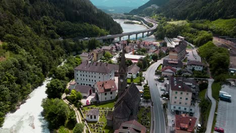 Aerial-View-of-small-Italy-Village-between-Green-Mountains,-near-the-blue-Eisack-river-stream,-tall-bridge-and-train-station---Beautiful-Scenic-View
