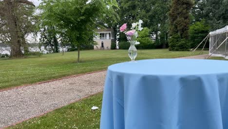 Blue-table-clothed-table-holds-a-flower-in-glass-as-a-building-in-background