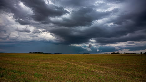 Dark,-stormy,-dramatic-thundercloud-cloudscape-over-farmland-fields---time-lapse