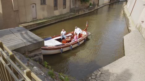 A-boat-with-three-passengers-is-gliding-under-a-bridge-in-Prague