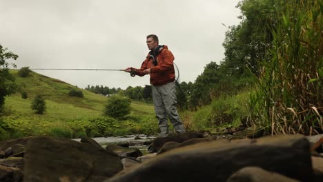 Low-angle-shot-of-a-fly-fisherman-casting-into-a-small-low-river-in-Scotland