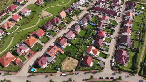 Residential-area-with-many-single-family-houses-with-green-gardens-in-a-small-town,-sunny-day,-drone,-outskirts-of-the-city