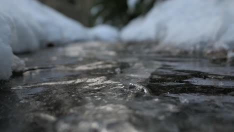 Water-streaming-under-ice,-frozen-stream-air-bubbles-flowing-under-ice