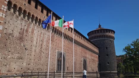 The-Italian,-English-and-European-flags-are-flying-at-Castello-sforzesco,-Milan