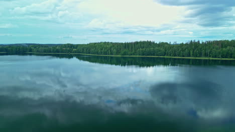A-Smooth-Shot-Of-A-Calm-Lake-Near-A-Large-Green-Forest-Landscape-On-A-Cloudy-Weather