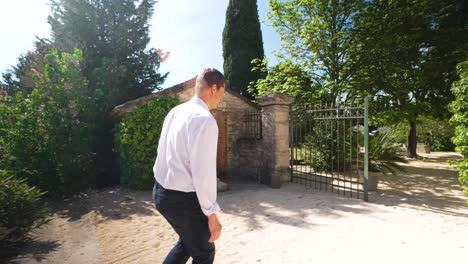 Slow-motion-shot-of-a-wealthy-villa-owner-walking-through-his-gates-in-Nimes