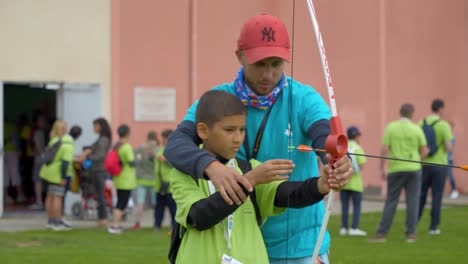 Hand-held-shot-of-an-instructor-teaching-a-child-archery-at-the-Narbonne-Handicapped-Event