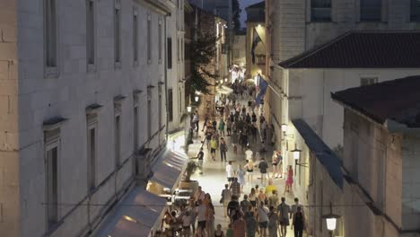 Nightlife-on-the-street-in-old-town-Zadar,-where-tourists-walk-on-whitewashed-stone-to-enjoy-history-in-the-cool-of-the-night