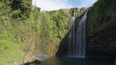 Wide-shot-of-Ogawa-falls-plunging-down-rock-face-into-pool,-Kagoshima-Japan