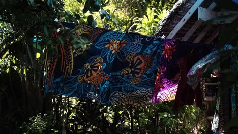 Traditionally-dyed-and-printed-tropical-sarong-with-vivid-turtle-and-flower-theme-on-a-line-blowing-in-the-wind