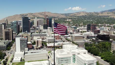 USA-Flag-on-Downtown-Skyline-Salt-Lake-City,-Utah-Building-Rooftop---Aerial