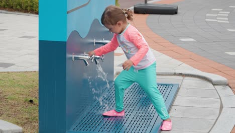 Süßes-Kleines-Kleinkindmädchen-Wäscht-Hände-Und-Beine-Auf-Dem-Wasserspielplatz-Der-öffentlichen-Parkwaschanlage