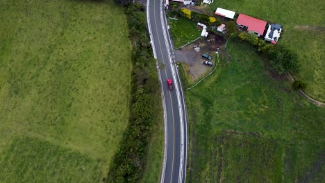 Experience-the-breathtaking-4K-aerial-view-as-a-drone-tracks-a-car-along-a-winding-road-surrounded-by-lush-nature