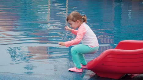 3-jähriges-Kleines-Mädchen-Reitet-Auf-Einem-Spielplatz-Im-Wasserpark-Im-Freien-Auf-Einer-Rutsche-–-Zeitlupe