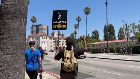 SAG-AFTRA-Striker-Picketing-and-Pumping-Fist-to-Oncoming-Traffic-Outside-Warner-Brothers-Studio-on-W-Olive-Ave