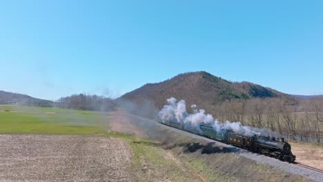 Aerial-View-of-EBT's-Narrow-Gauge-Restored-Antique-Steam-Passenger-Train-Approaching,-Going-Upgrade-With-Steam-and-Smoke-on-a-Clear-Sunny-Day