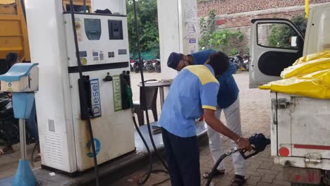 Zapfsäulenarbeiter-Füllt-Benzin-Ins-Auto-Und-Fahrer-Notiert-Den-Benzinstand-Per-Handy