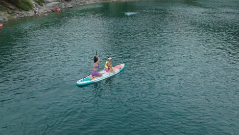 Two-Asian-girls-setting-off-from-lake-shore-on-a-colorful-SUP-board