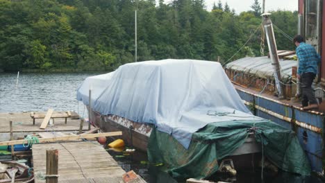 A-man-mooring-a-wooden-boat-with-covers-to-a-dock