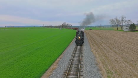 A-Head-on-Drone-View-of-an-Antique-Steam-Passenger-Train-Approaching-While-Traveling-Thru-Farmlands-on-a-April-Day