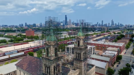 Flying-in-middle-of-scaffolding-of-the-St-Adalbert-Church,-toward-the-skyline-of-Chicago,-USA---Aerial-view