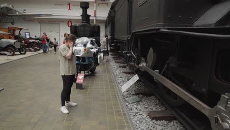 Woman-watching-old,-historical-locomotive-on-display-in-National-Technical-Museum-in-Prague,-Czech-Republic