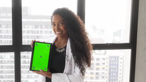 beautiful-black-woman-holding-tablet-green-background-vertical-smiling