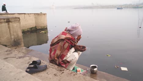 An-old-Hindu-man-offering-prayers-on-Yamuna-river-ghat-in-Delhi-India