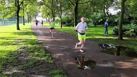 Slow-motion-group-of-people-running-in-charity-competition-in-shaded-public-park