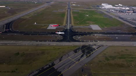 Airplane-arriving-and-taxiing-towards-Iceland-airport-terminal,-aerial