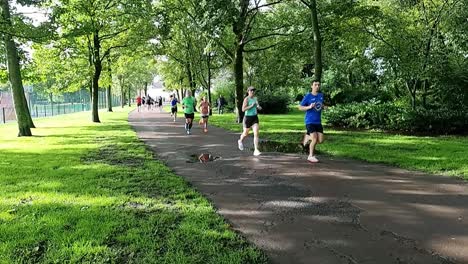 Slow-motion-group-of-sporty-people-running-in-charity-marathon-in-shaded-public-park