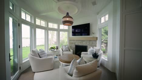 Cozy-circular-hearth-room-with-white-chairs,-natural-light-windows,-and-television