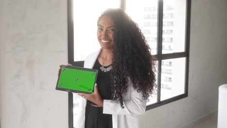 Schöne-Schwarze-Frau-Hält-Tablet-Mit-Grünem-Hintergrund-Und-Lächelt-Horizontal