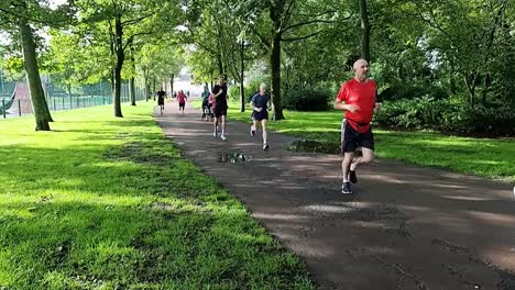Slow-motion-sporty-group-of-people-running-in-charity-marathon-in-shaded-public-park