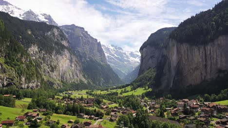 Vista-Aérea:-Valle-De-Lauterbrunnen-En-Suiza-En-Un-Día-Soleado,-Famoso-Destino-Turístico,-Pueblo-Alpino-De-La-Cascada-Suiza-De-Staubbach-Con-Pinos,-Montañas-Y-Pintorescos-Prados-Verdes