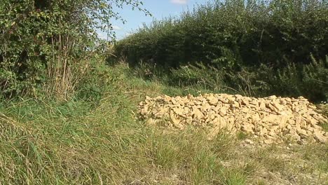 An-entrance-to-a-field-in-the-rural-county-of-Rutland-in-the-United-Kingdom-obstructed-by-using-a-load-of-sandstone-at-the-entrance-to-prevent-vehicles-from-going-into-the-field
