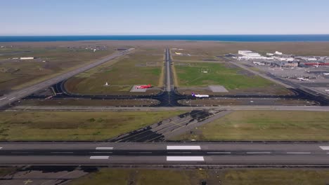 Keflavik-International-Airport-in-Iceland-on-sunny-day,-airplane-taxiing,-aerial-shot