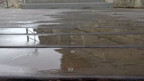 Rain-drops-pouring-and-bouncing-on-a-wooden-planked-terrace