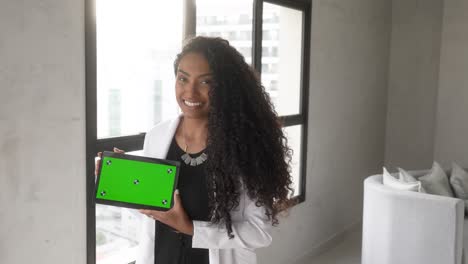 beautiful-black-woman-holding-tablet-green-background-horizontal-smiling