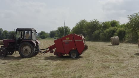 Tractor-with-hay-baler-machine-at-work-in-rural-agricultural-scene