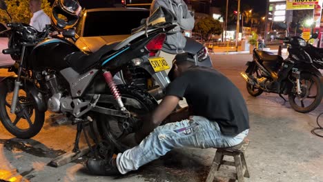 Young-mechanic-fixing-a-motorcycle-wheel-on-a-gas-station_Service-man