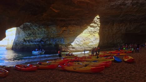 People-Gathering-Near-Kayaks-Under-Beautiful-Cave-On-Sandy-Beach,-Benagil,-Portugal