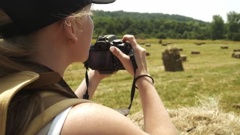 Girl-hiker-takes-photos-in-rural-agricultural-scene-with-golden-hay-bales