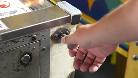 gamer-hand-pull-and-drop-the-launch-plunger-of-a-pinball-machine-flipper,-close-up-handheld-slow-motion-shot