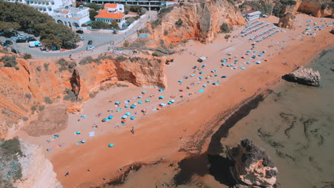 Gente-Caminando-Por-La-Playa-Durante-El-Verano-En-Praia-Dona-Ana-En-El-Algarve-En-Portugal,-Vista-Aérea-De-Drones