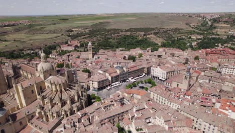 Aerial-View-Over-Plaza-Mayor-Beside-Segovia-Cathedral-On-Sunny-Day-With-Rural-Fields-In-Distant-Background