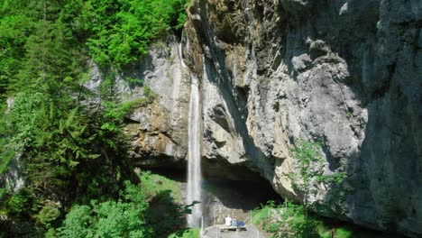 People-Sitting-On-The-Viewing-Platform,-Admiring-Berglistuber-Waterfall-In-The-Canton-of-Glarus-In-Switzerland