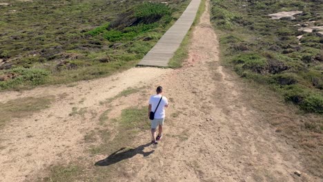 Aerial-View-Of-A-Man-Walking-To-The-Wooden-Path-On-A-Sunny-Day-In-Summer
