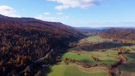 Amazing-scenery-of-green-field-in-a-valley-and-forested-hills,-warm-fall-colours,-Slovenia